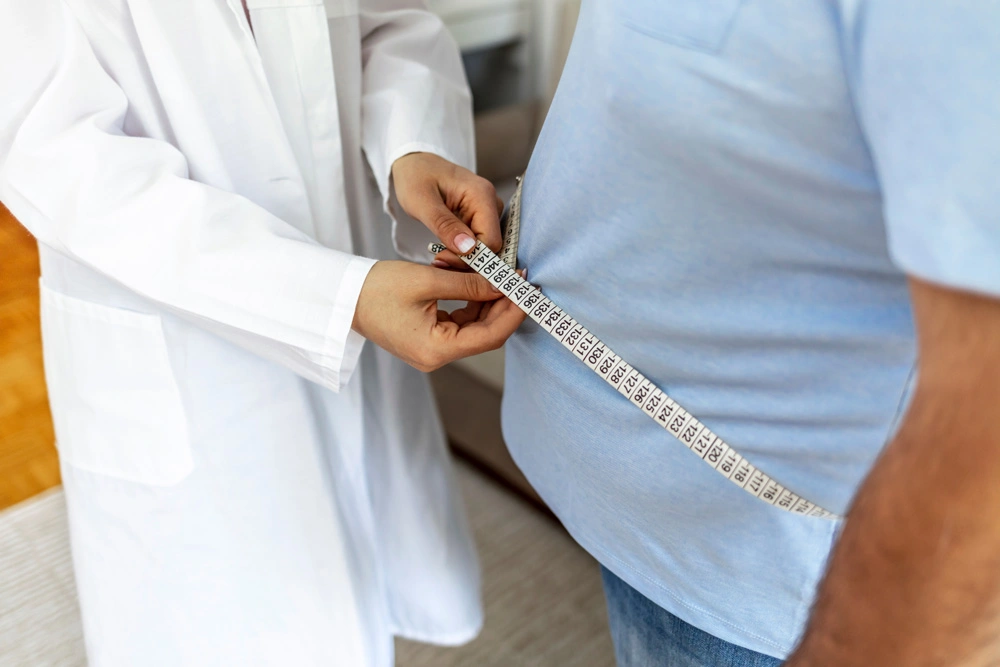 Women doctor measuring overweight man in clinic.