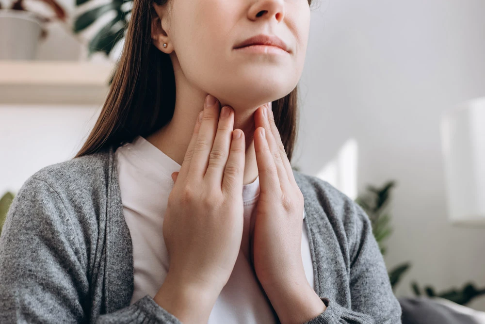 Selective focus of unhealthy sad young caucasian woman hold hands over sore throat feeling discomfort.