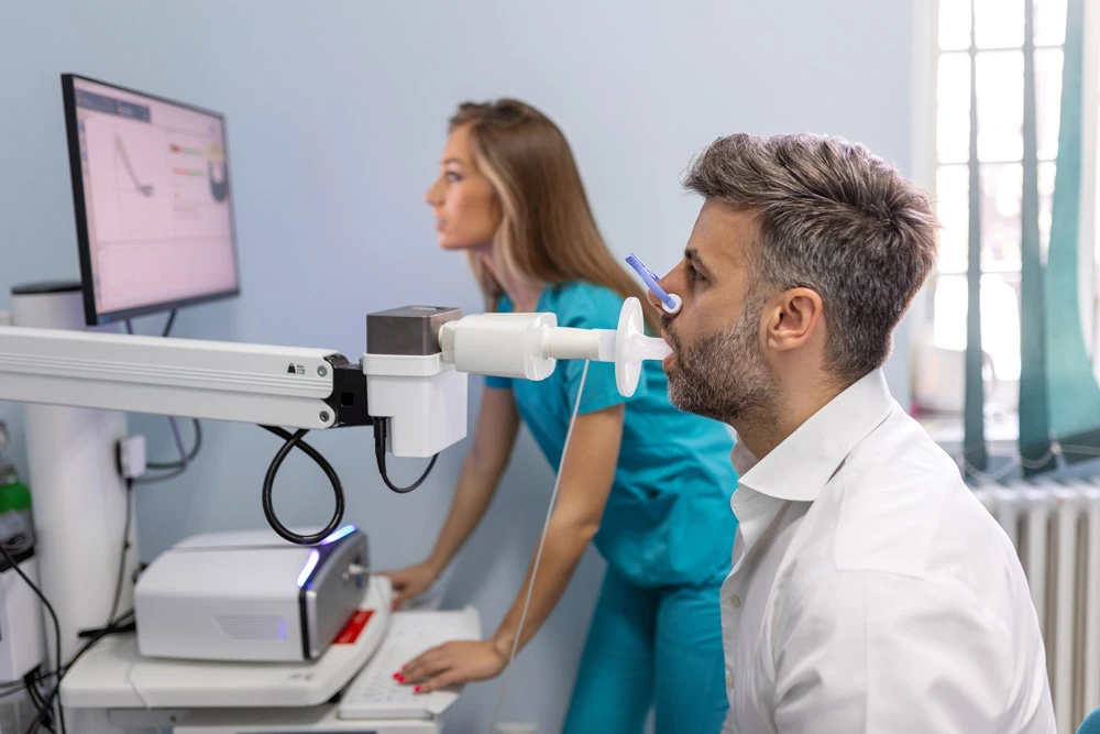 Man performing pulmonary function test and spirometry using spirometer at medical clinic.