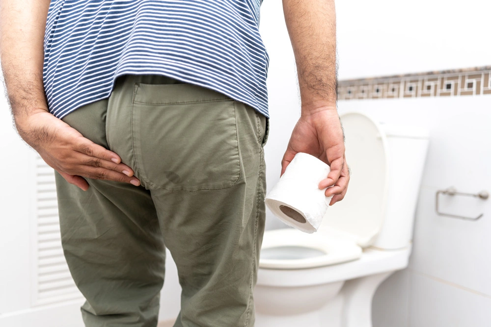 Male suffers from diarrhea holds toilet paper roll in front toilet bowl