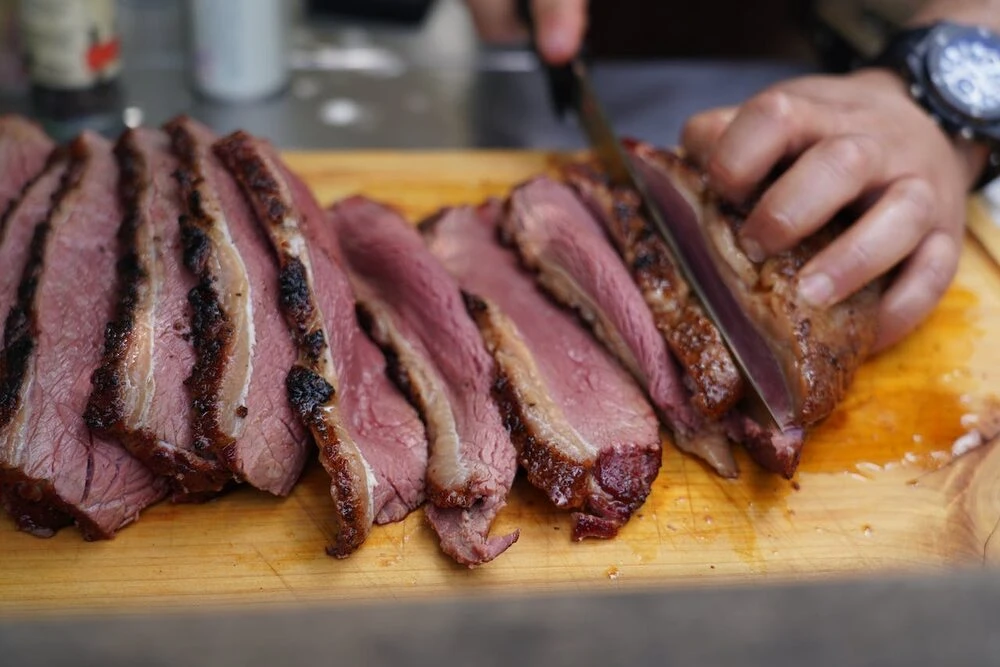 Red meat being sliced on a chopping board