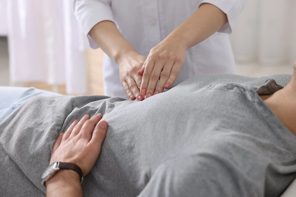 Gastroenterologist examining patient with stomach pain in clinic