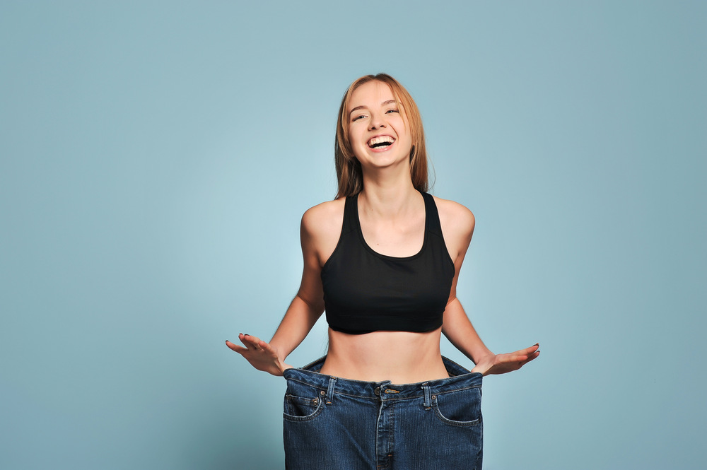 Women shows her weight loss. Isolated on blue background