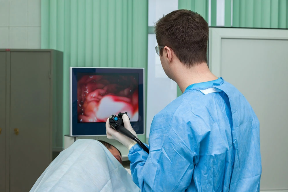A gastroenterologist with an endoscope in his hands examines the patient