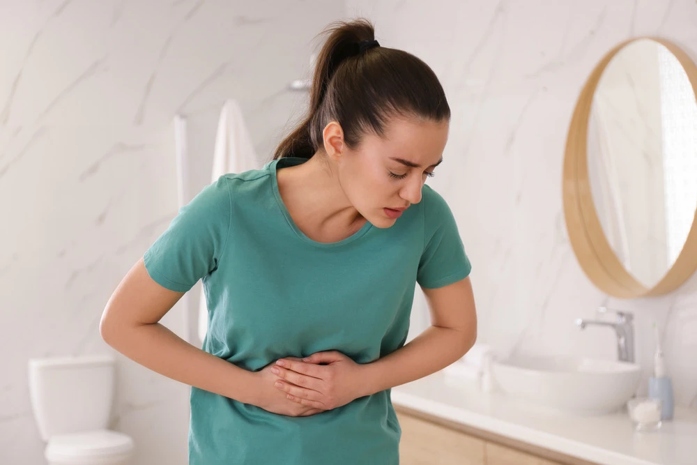 Young woman suffering from stomach ache in bathroom.