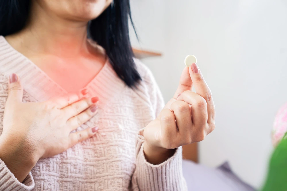 Woman holding a tablet medication for heartburn