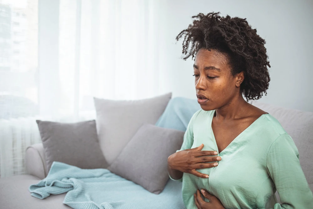 Pressure in the chest. Close-up of a stressed woman who is suffering from a chest pain and touching her heart area