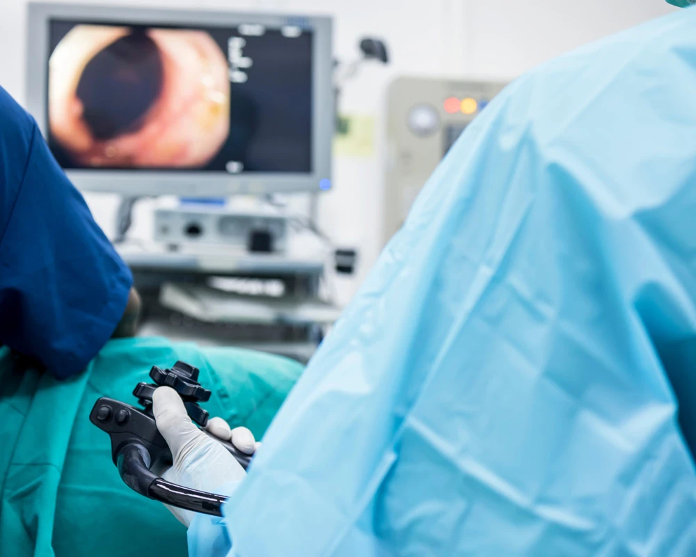 A doctor or surgeon in a light blue protective gown did a colonoscopy or gastroscopy inside operating theatre in the hospital.