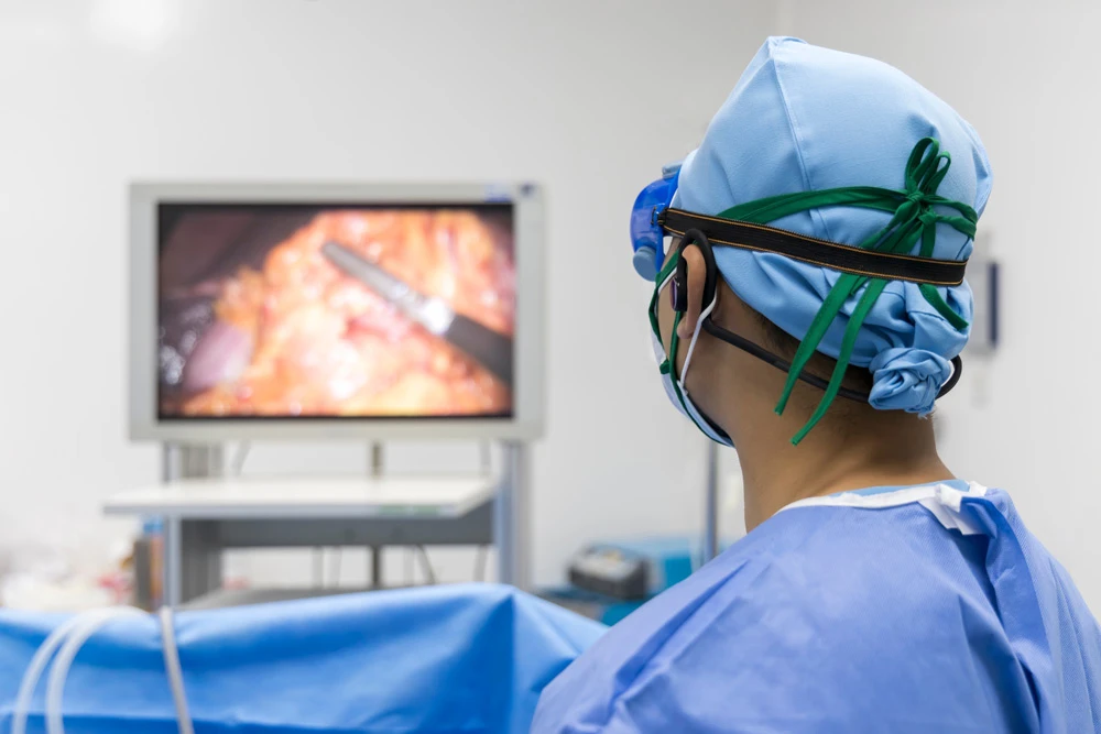 Doctor or surgeon in blue uniform looking at monitor screen in operating room at hospital.