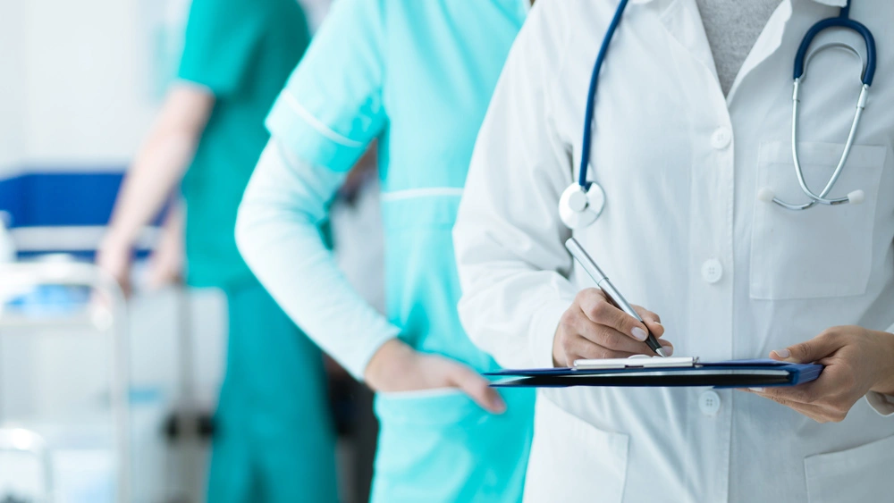 Medical staff working at the hospital: doctor and nurse checking a patient's medical record on a clipboard, healthcare and medical exams concept