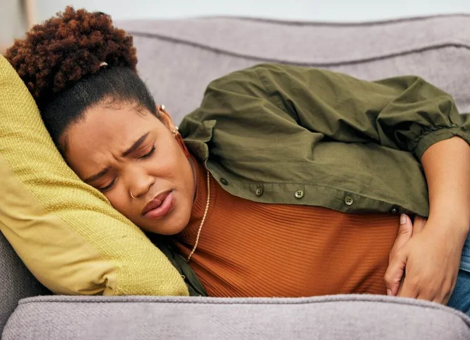 Sick woman, stomach pain and problem on sofa for ibs