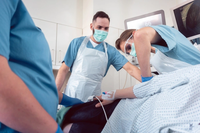 Doctor in surgery of hospital performing colonoscopy at sedated patient