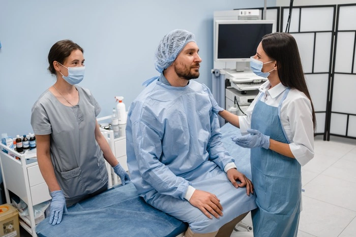 Female doctor and nurse assistant talking asking about feelings a male patient after colonoscopy or gastroscopy examination